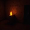 A Minecraft torch on a stone wall lighting a dark mine tunnel with coal ore nearby